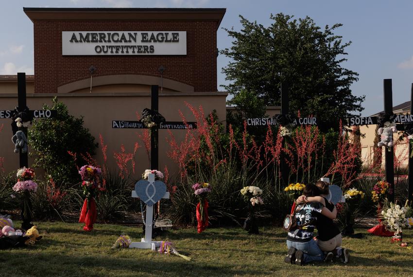 People embrace each other as they mourn the eight people who died in the Allen Premium Outlets shooting at a memorial in Allen, TX on May 8, 2023.