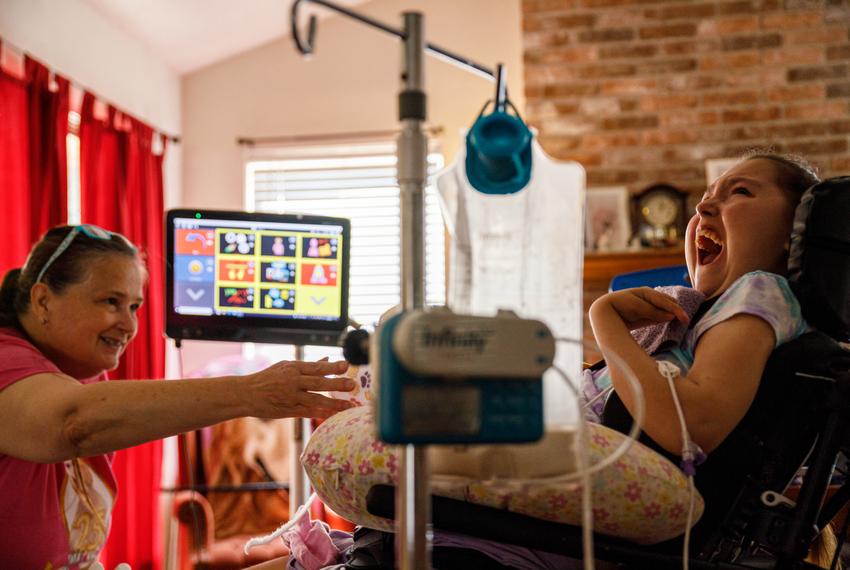 Laurie Sharp talks with her daughter, Logan Sharp, in the living room of their Pflugerville home on Sep. 9. 2023. Logan's feeding tube runs in the foreground, which she requires to eat.