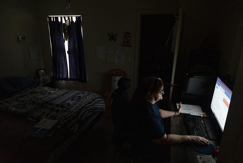 Terri Rimmer uses her computer to search for remote jobs and browse the internet in her apartment in Fort Worth on Sept. 9, 2023. A black out curtain on the window helps keep the room cool.