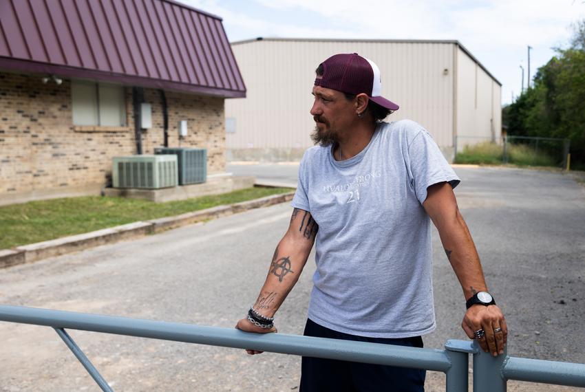 Brett Cross leans on a new gate next to the Uvalde CISD Administration building on Oct. 4, 2022. Cross has been staying on the property in protest of UCISD's failure to suspend the school officers who were present at the school shooting at Robb Elementary.