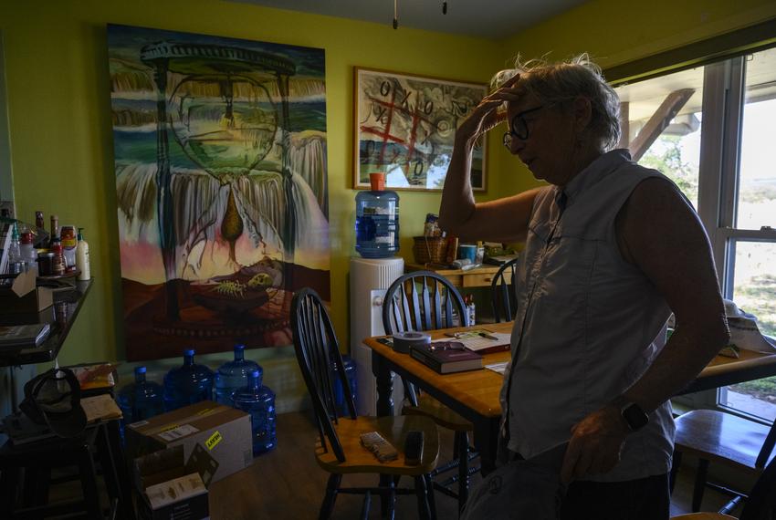 Linda Fawcett stands in front of her painting “Water Witch,” in her dining room Wednesday, Sept. 20, 2023, in Junction. Named after the moniker used to describe a person who used dowsing rods to search for water underground, the painting depicts Fawcett’s biggest fear of the Llano River going dry.