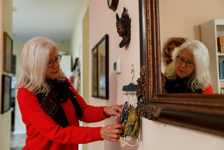 Alice Barton looks through a rack of homemade masks in her South Austin home on Nov. 10, 2023. Barton, a retired  physician, continues to take COVID precautions such as masking.