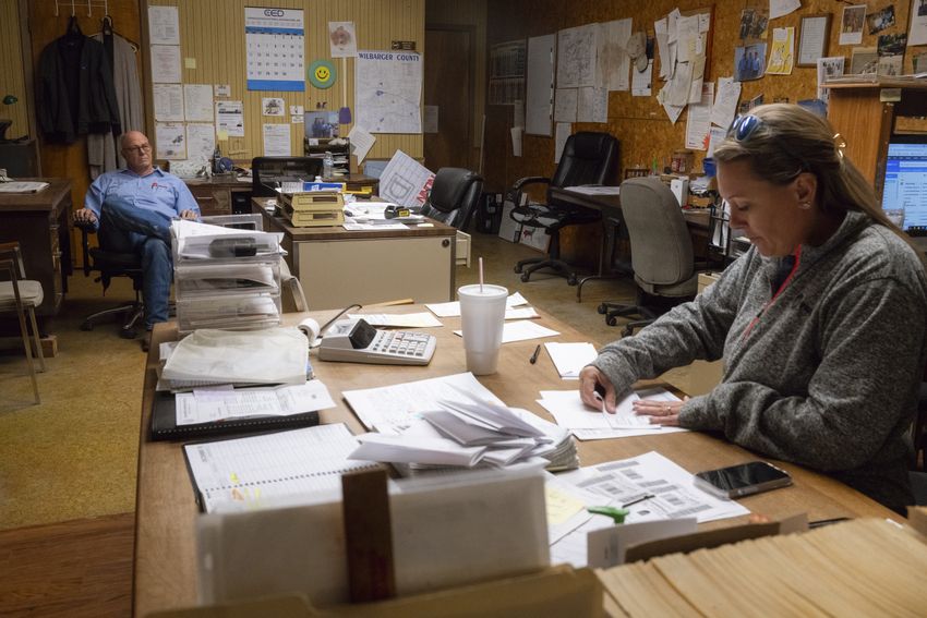 Danny Fancher, 69, owner  of Fancher Electric, left, watches as his daughter, Krystal Fancher Smith, 41, completes payroll and invoicing inside the company office on Thursday, November 30, 2023 in Vernon. Smith never finished college, but instead plans to take over the family business in the future.