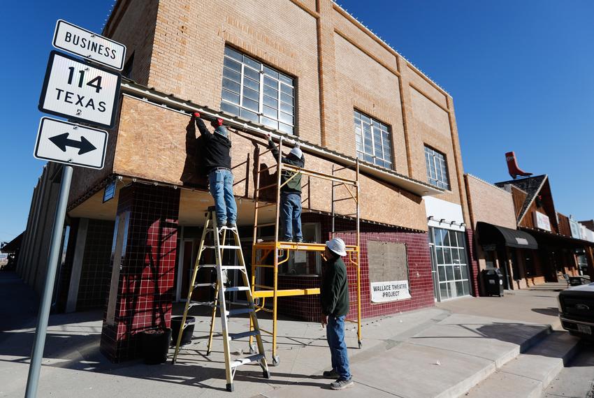 Workers remove a plywood covering on the front of the Wallace Theater in Levelland on Dec. 5th, 2023. The historic theater, which has been vacant since the 1980s, is now under restoration and is expected to reopen by Dec. 2024.