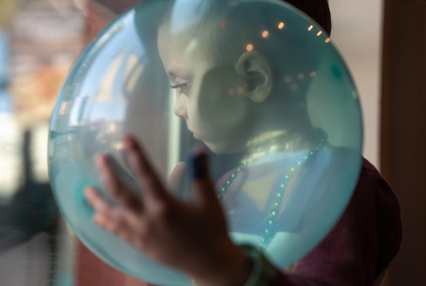 August looks through the glass door of the birthday venue while cradling a balloon on Dec. 9, 2023.