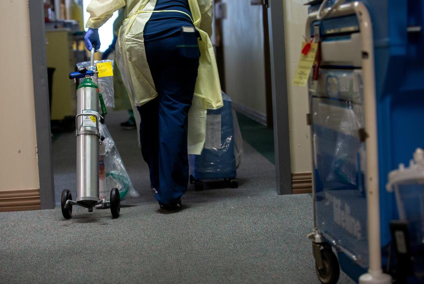 Healthcare workers wheel portable oxygen tanks to patients in the COVID care unit of Titus Regional Medical Center in Mount Pleasant on Aug. 19, 2021.