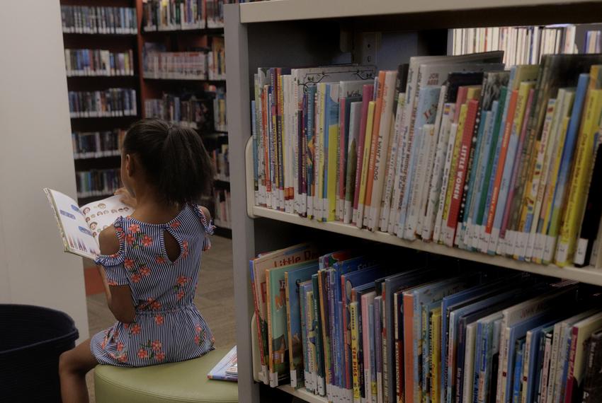 Sharby Hunt-Hart’s 7-year-old daughter reads a book at the Rowlett Public Library in Rowlett, TX on October 26, 2023.