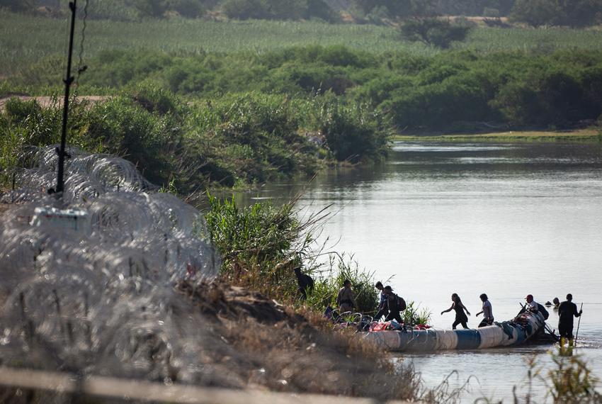 Migrants are directed by a DPS Trooper around floating barrels covered in razor wire in the Rio Grande, on July 22, 2023, in Eagle Pass.