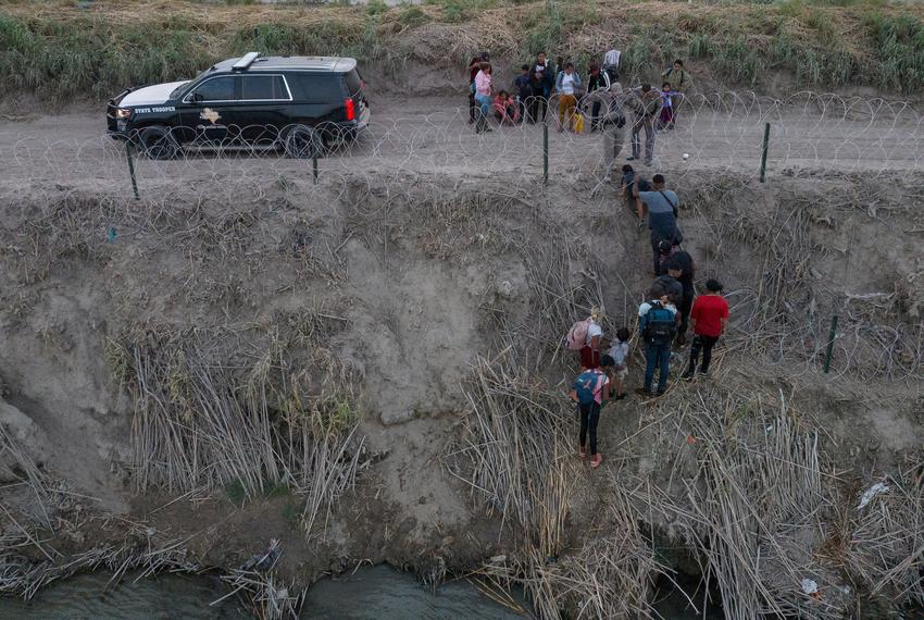 Texas Department of Public Safety troopers pull migrants from under concertina wire after they crossed the Rio Grande River from Mexico into Eagle Pass, on July 27, 2023.