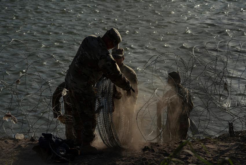 National Guard members install concertina wire along the river bank on private property owned by the Urbinas in Eagle Pass, Texas on July 28, 2023. 
Verónica G. Cárdenas for The Texas Tribune