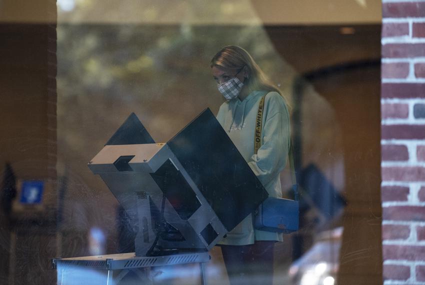 A young women wearing a face covering votes inside the polling location at University Park United Methodist Church in Dallas, on Nov. 3, 2020.
