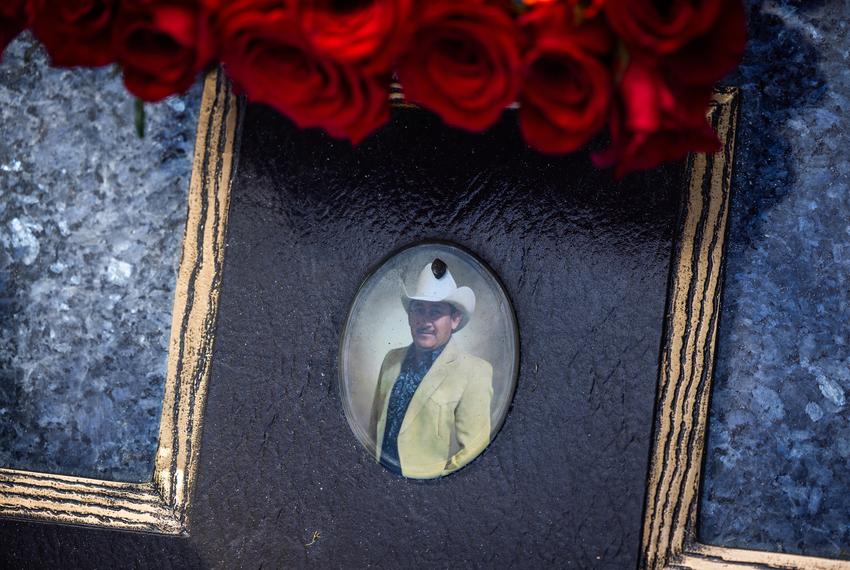 Photograph of Eliberto Ortega on top of his gravestone on the Día de los Muertos, Thursday, Nov. 2, 2023, in Houston. Ortega died of cardiac arrest while sick with the coronavirus in July 2021. (Marie D. De Jesús / Houston Landing)