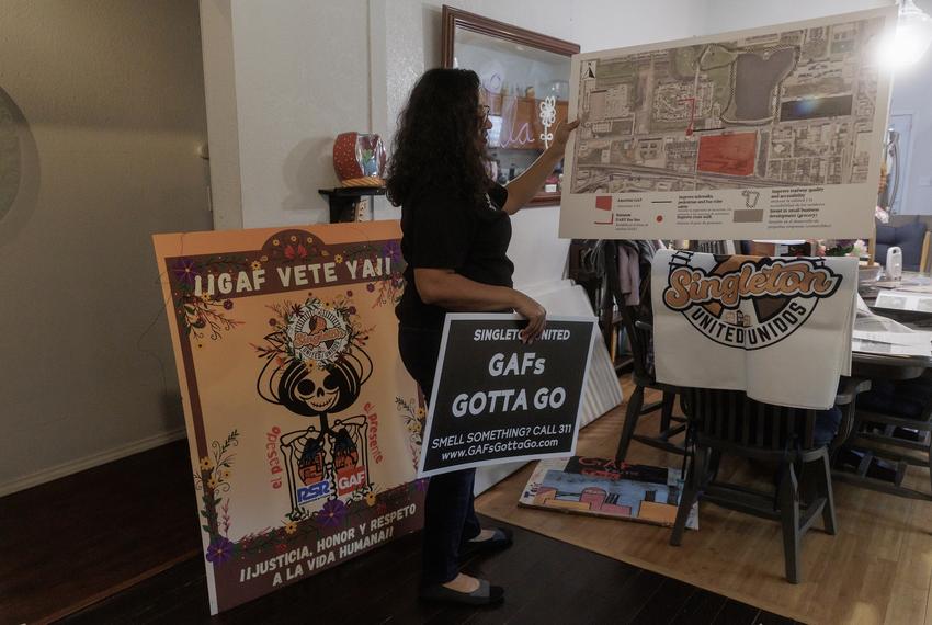 Janie Cisneros shows different signs she and other activists have made while protesting the GAF shingles factory inside of her home in West Dallas on Dec. 13, 2023.