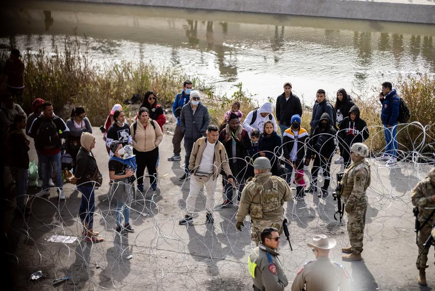 Migrants standing on the other side of barbwire speak to the Texas National Guard and Texas DPS officers along the banks of the Rio Grande, Tuesday, December 20, 2022, in El Paso, Texas. Over 400 personnel have been sent to this border sector by Governor Abbott after El Paso city officials declared a state of emergency. Photo by Ivan Pierre Aguirre for The Texas Tribune