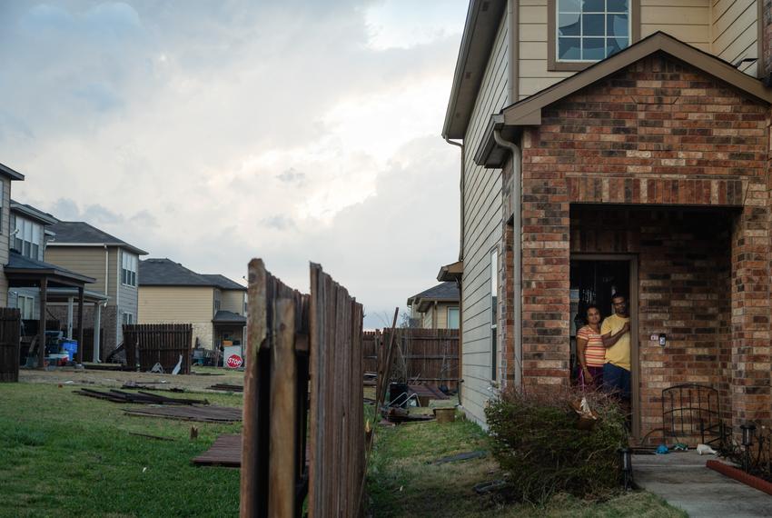 A family watches from their door as people assess damage after a tornado moved through Round Rock on March 21, 2022.