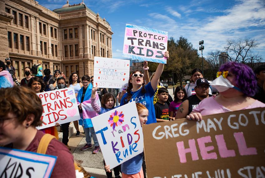 Ashley (middle) chants, "God made trans kids! God loves trans kids!" with her children during a protest at the Texas Capitol on Tuesday, Mar. 1, 2022.