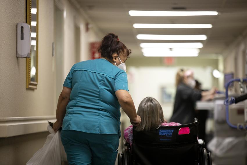 Norma Gonzales, the housekeeping supervisor of Amistad Nursing and Rehabilitation Center, walks with Ursula Sinko, a resident of the facility, on April 1, 2021.