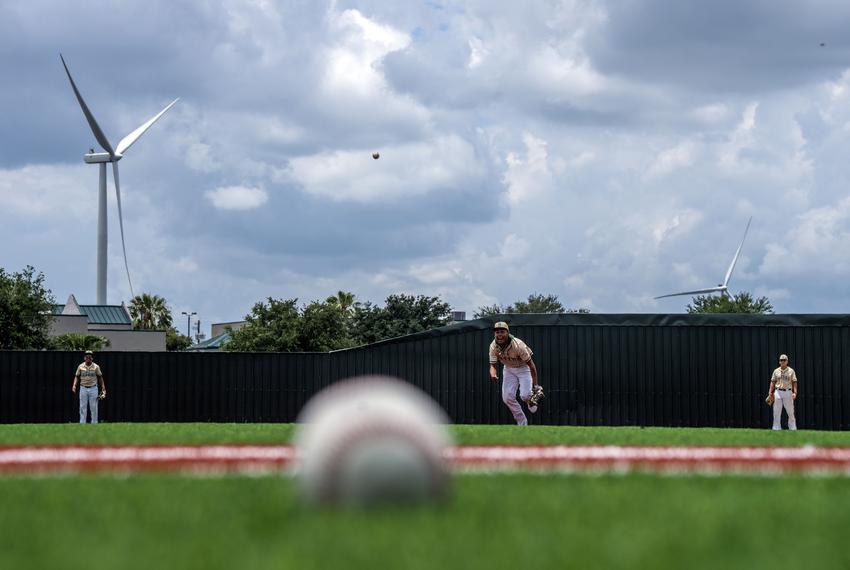 Lyford, TX - May 17, 2023: Members of the Lyford high-school baseball team practice of a new athletic field partially funded by wind turbine tax bonds in Lyford, TX. Industrial energy-producing wind turbines cover hundreds of acres of farmland in Lyford, TX. (Photo by Ben Lowy for The Texas Tribune)